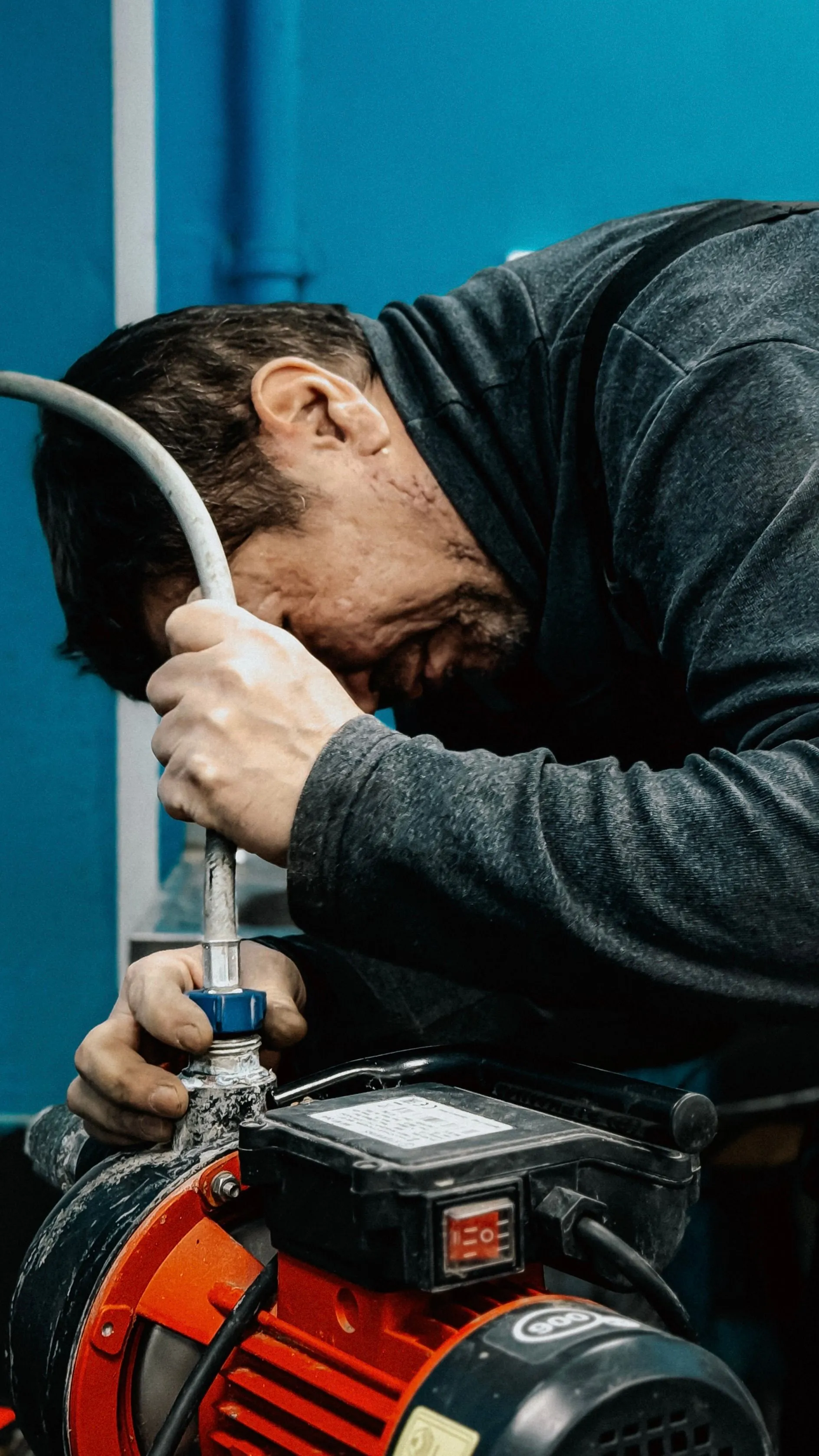 A technician leaning in to tighten a fitting on a water pump